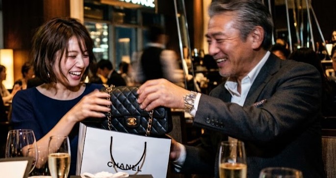 お金持ちのパパから高級バッグのプレゼントをもらっているシーンのイメージ写真